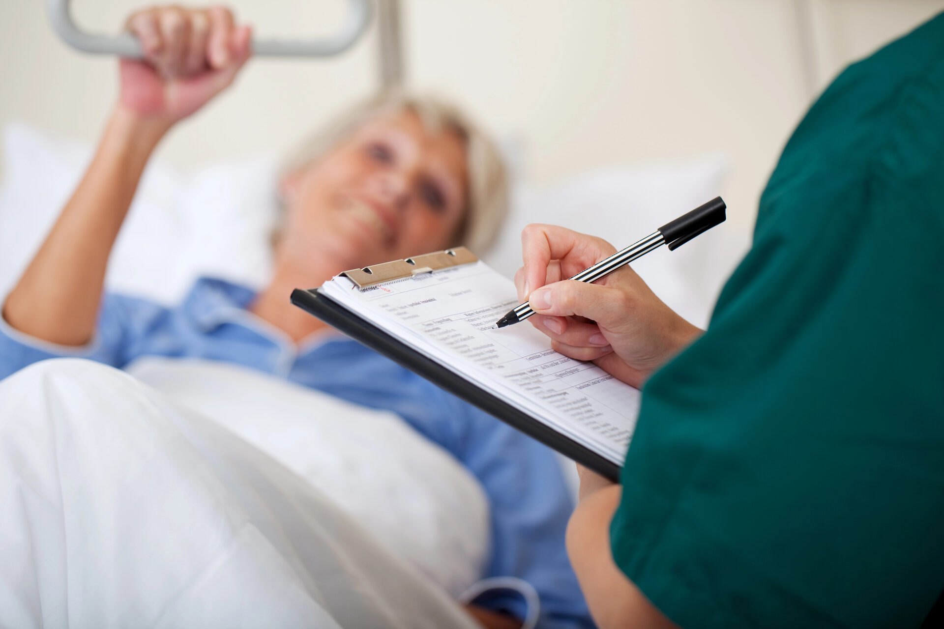 Doctor writing on clipboard while speaking with a patient